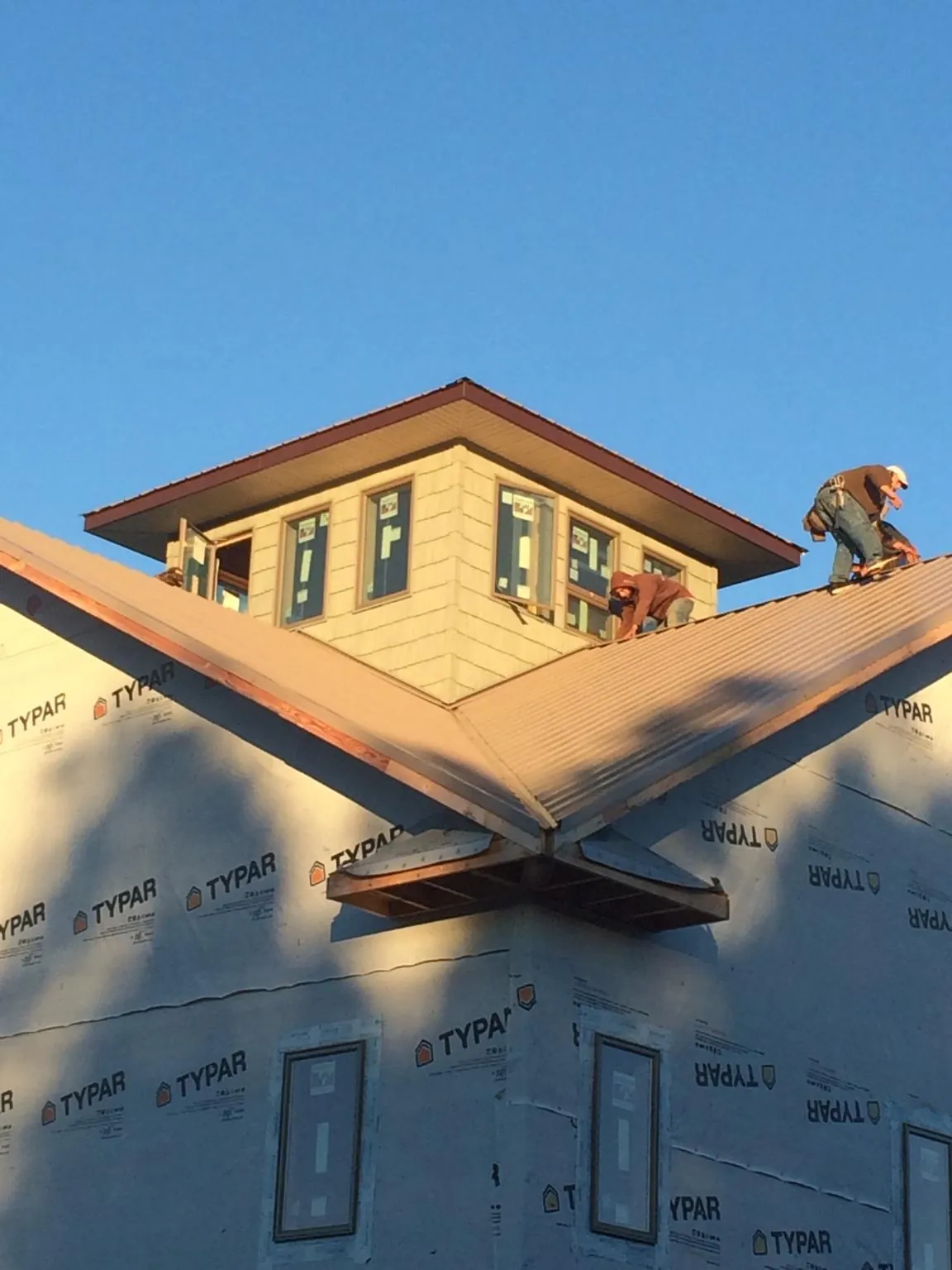 Roofers working around a rooftop cupola on a new metal roof at sunset — Roof Waterproofing in Smithville by Roofing Brothers